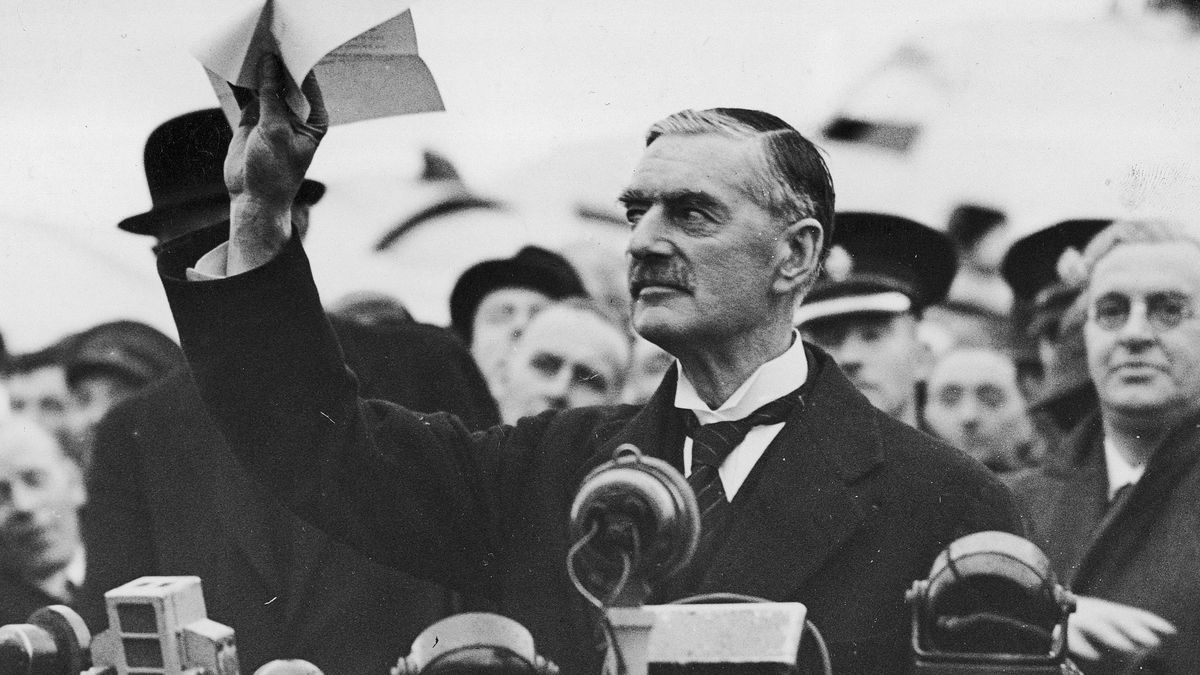 Neville Chamberlain drží nad hlavou list papíru před davem a mikrofony